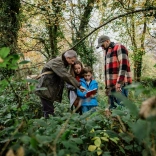 A family with a young boy In the woodswith a forager guide showing them a guide book