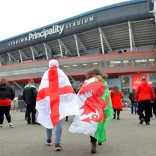 man wearing England flag and woman wearing Welsh flag walk towards Principality Stadium, Cardiff.